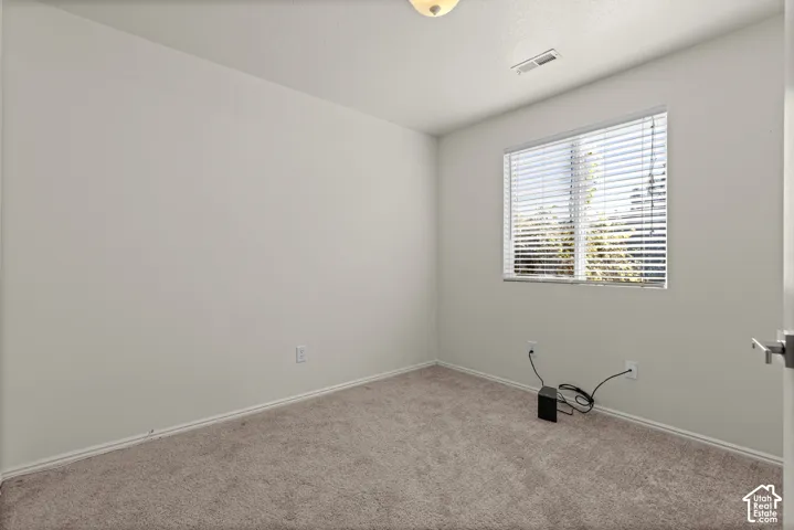 Neutral-toned room featuring neutral carpeting, a single-pane window with horizontal blinds, and a semi-flush mount ceiling light fixture