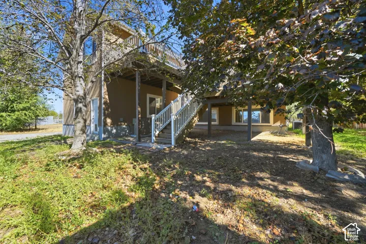 Exterior facade featuring a raised wood deck with white railings, an external staircase, and covered ground-level patio space