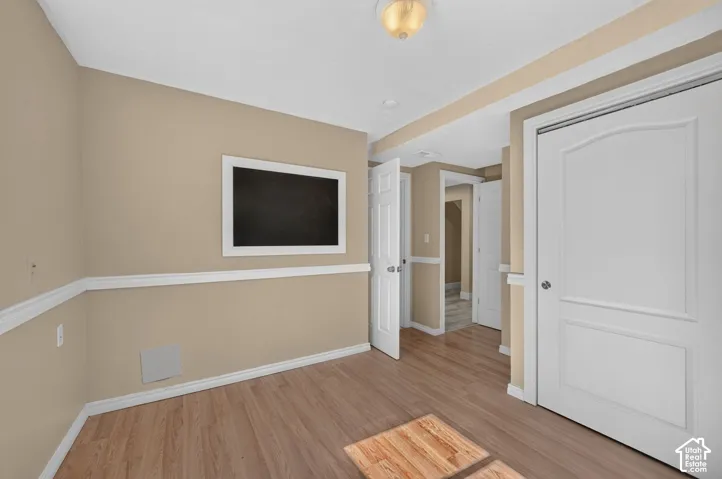 Interior space featuring wood-finish flooring, crisp white chair rail molding, a neutral color palette, and multi-panel interior doors