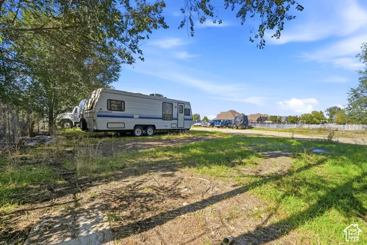 Expansive outdoor area featuring mature trees, partial fencing, and natural ground cover