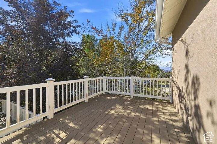Elevated deck featuring composite decking, white railing with square balusters, and stucco siding