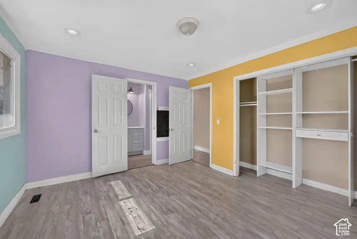 Room interior featuring wood-finish flooring, recessed lighting, and a built-in closet system with integrated shelving