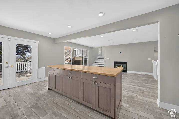 Kitchen island featuring wood-finish countertops and cabinetry, wood-finish flooring, recessed lighting, and a fireplace