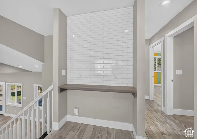 Built-in wood-finish shelving featuring white subway tile backsplash, recessed lighting, and wood-finish flooring