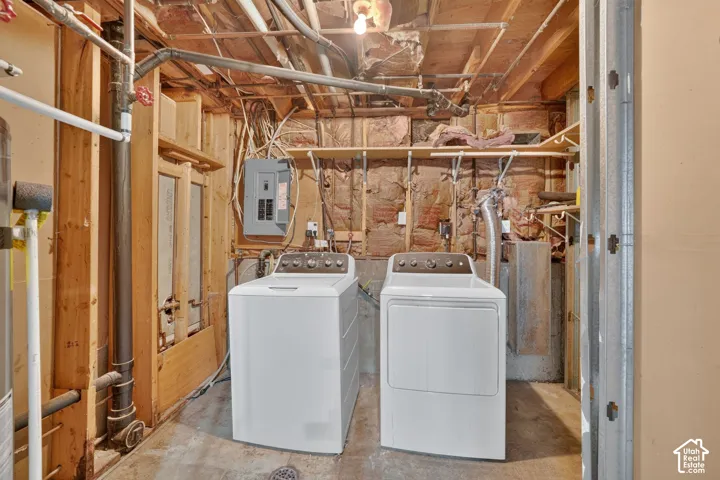 Utility area featuring exposed timber framing, concrete flooring, wall-mounted electrical panel, and built-in wood shelving