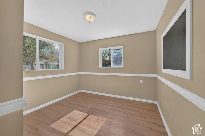 Room featuring wood-finish flooring, white chair rail molding, dual windows, and a built-in wall-mounted chalkboard