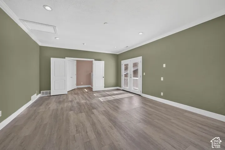 Interior space featuring wood-finish flooring, recessed lighting, double-door access to an exterior balcony, and crown molding