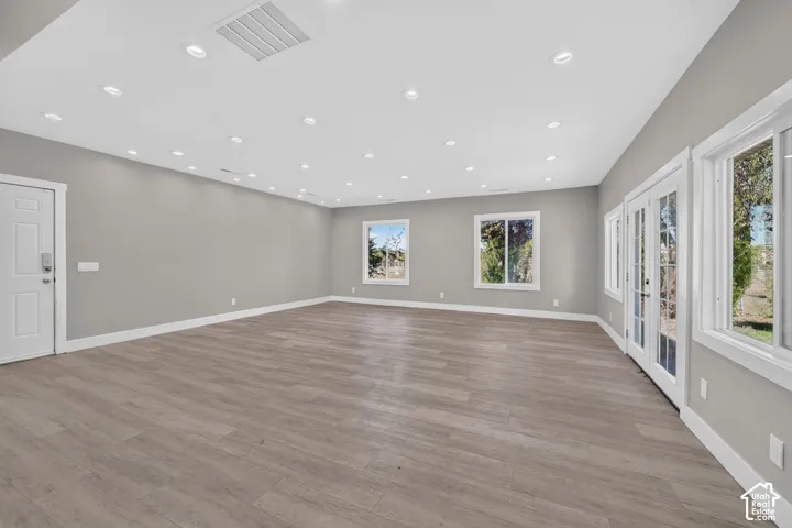 Spacious interior featuring wood-finish flooring, neutral wall paint, recessed lighting, double-pane windows, and glass-paneled exterior doors
