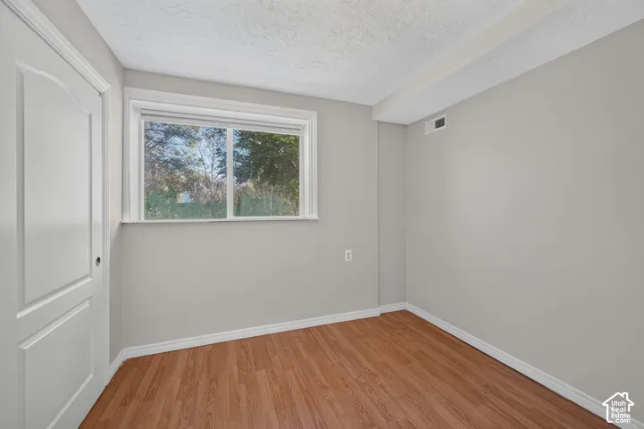 Neutral-toned interior featuring wood-finish flooring, a two-panel interior door, and a single-pane sliding window