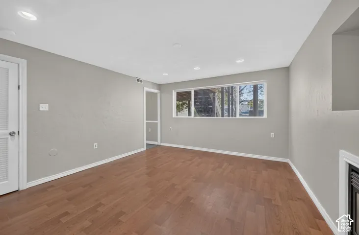 Interior room featuring wood-finish flooring, recessed lighting, neutral wall paint, and a large picture window