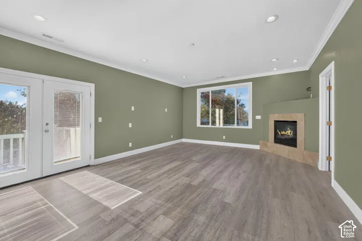 Wood-finish flooring, recessed lighting, crown molding, stone-surround fireplace, and double glass-pane doors