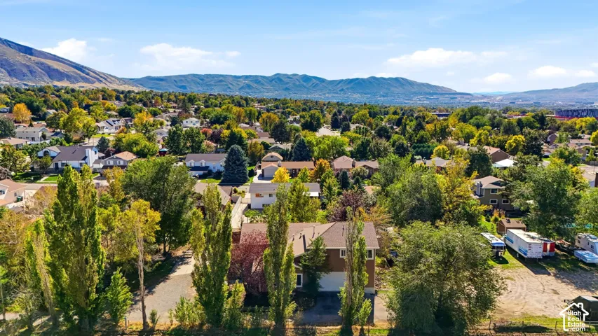Aerial perspective featuring a multi-level home exterior, expansive grounds with mature trees, and prominent mountain backdrop