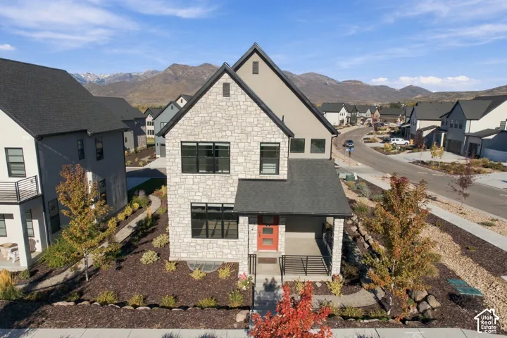 Two-story residence featuring a mixed stone and stucco exterior, covered front porch with iron railings, and mountain backdrop