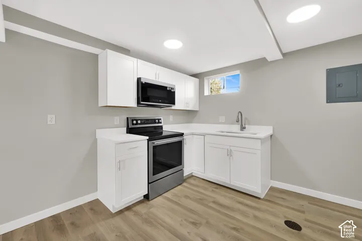 Kitchenette featuring white cabinetry, solid-surface countertops, wood-finish flooring, stainless steel range, and built-in microwave