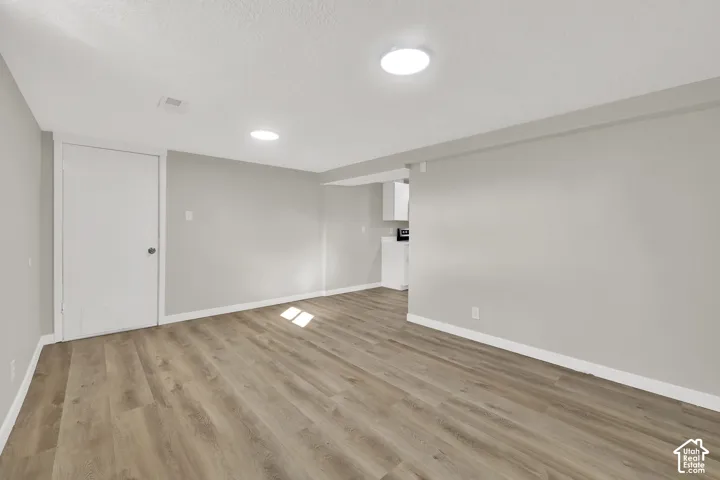 Neutral-toned interior featuring wood-finish flooring, recessed lighting, and white door hardware