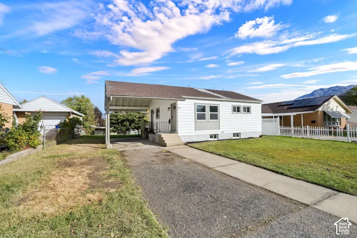 Exterior featuring white horizontal siding, attached carport, asphalt driveway, concrete walkway, and mountain scenery