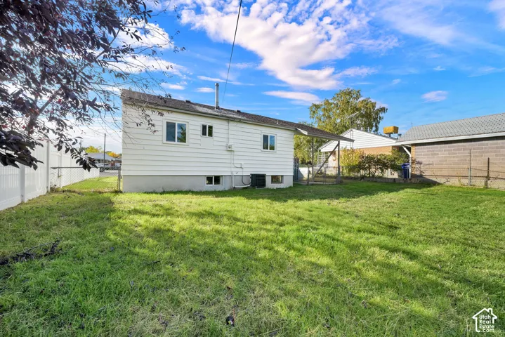 Exterior of home featuring white horizontal siding, an attached covered patio, and a grass-covered backyard enclosed by a vinyl fence