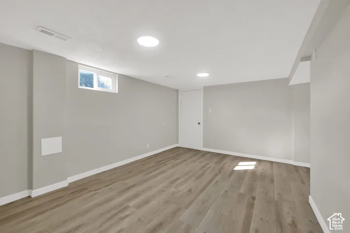Neutral-toned interior featuring wood-finish flooring, recessed lighting, and a single egress window