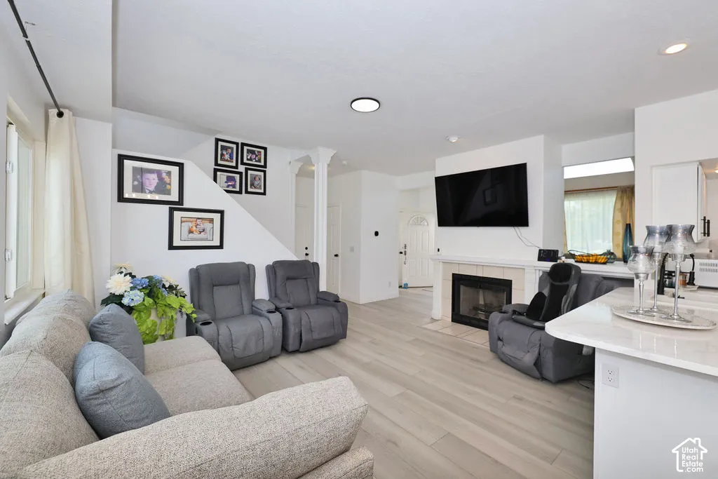 Open-concept room featuring light wood-finish flooring, a neutral color palette, and a fireplace with a tiled surround