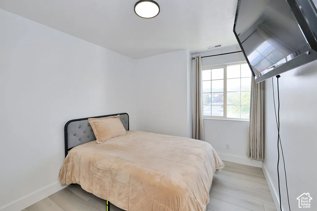 Neutral-toned interior featuring wood-finish flooring, a multi-pane window with grid detailing, and a flush-mount ceiling light fixture