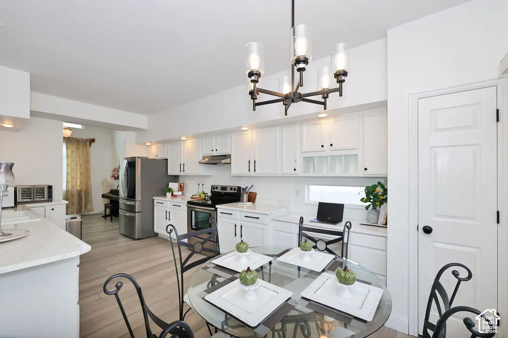 Kitchen featuring white cabinetry, solid-surface countertops, wood-finish flooring, and a multi-light metal chandelier