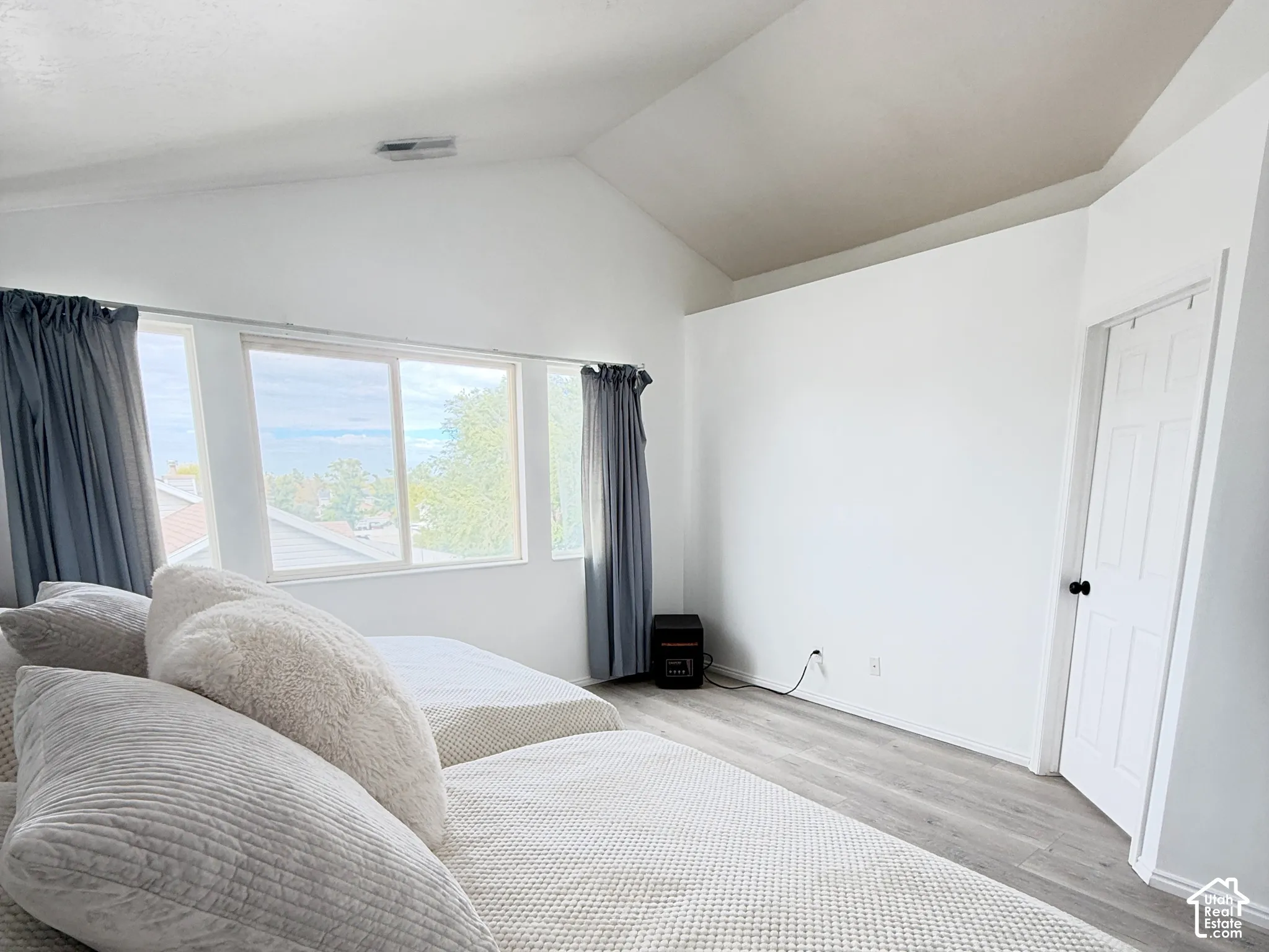 Vaulted ceilings with flush-mount lighting, wood-finish flooring, and expansive windows featuring horizontal sliding glass panels