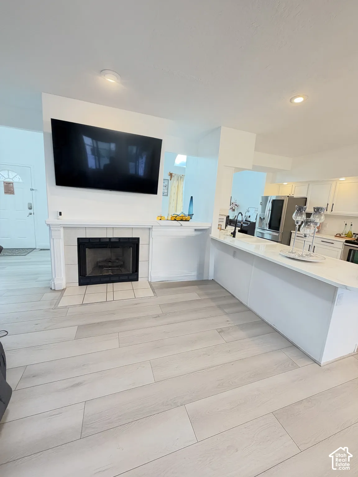Fireplace with tile surround, wood-finish flooring, recessed lighting, and kitchen island with stone countertop