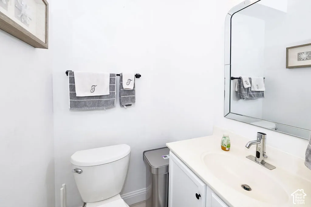 Bathroom featuring a vanity with an integrated sink, polished chrome faucet, white cabinetry, and a frameless, rounded-corner mirror