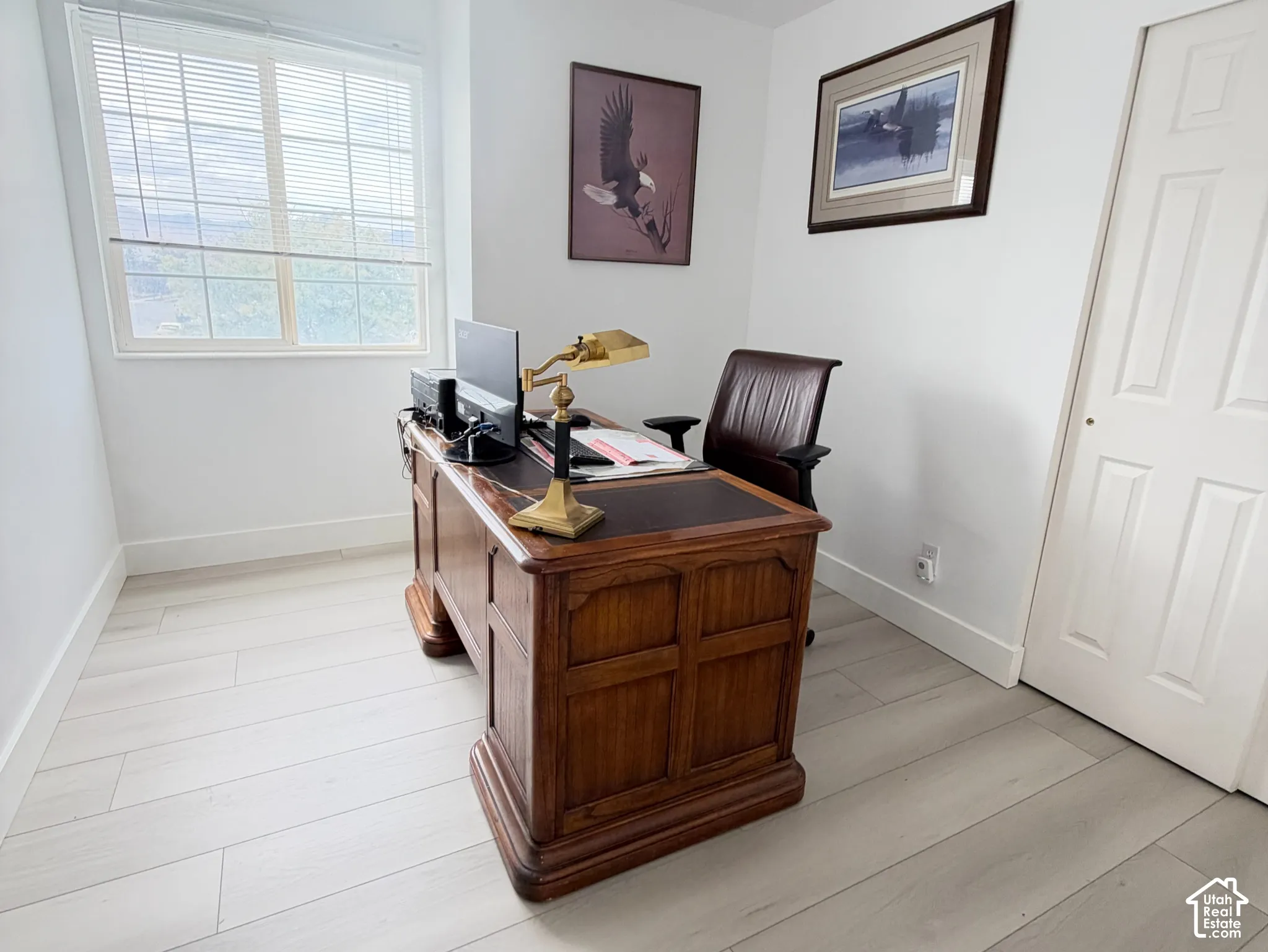 Bedroom/ Office Room featuring light-toned wood-finish flooring, a large window with horizontal blinds, neutral wall paint, and a classic four-panel interior door