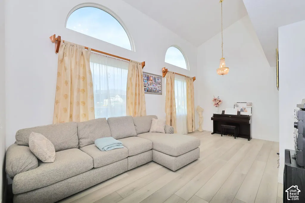 Vaulted ceilings featuring dual arched windows, wood-finish flooring, and a decorative hanging light fixture