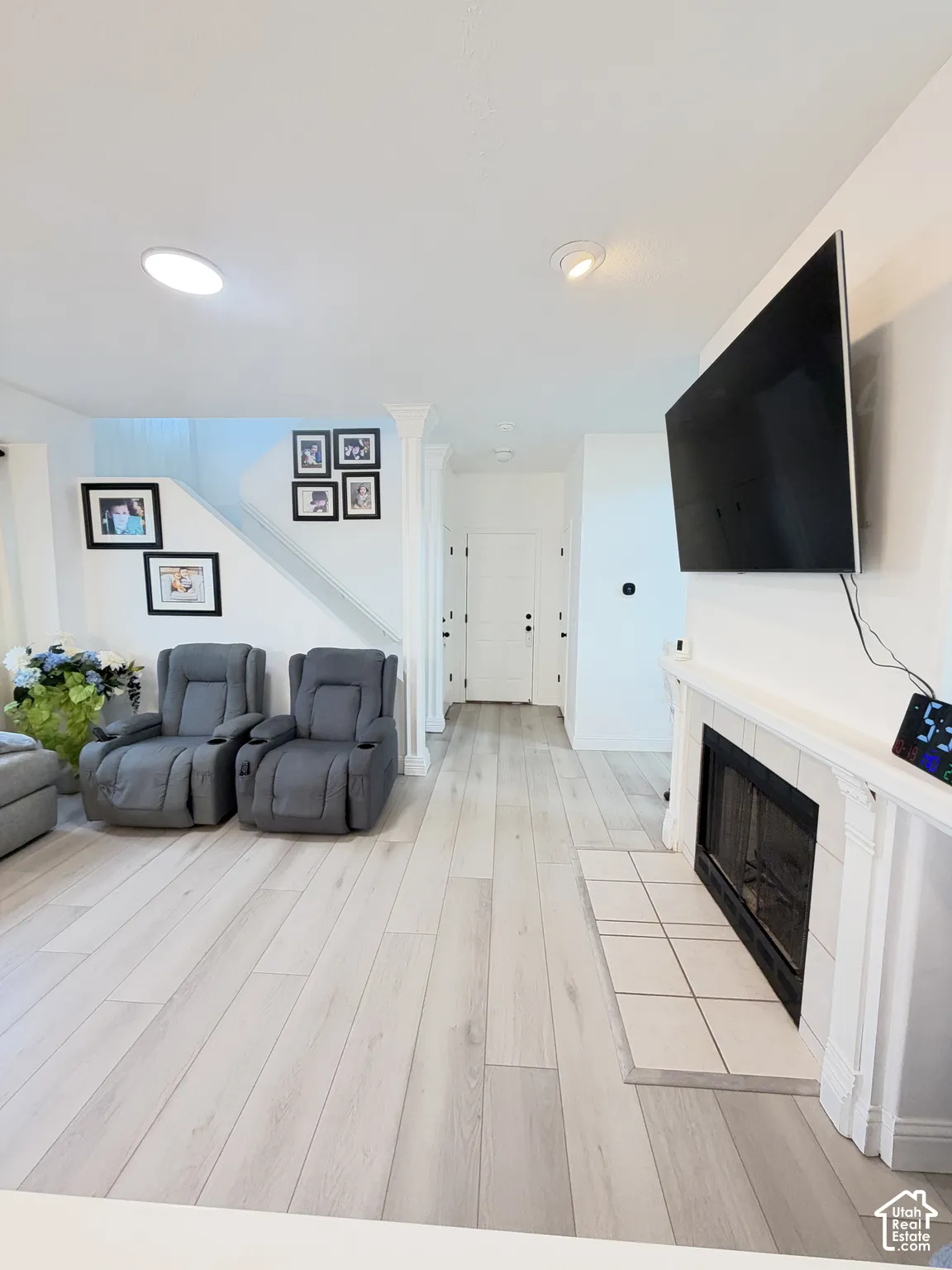 Interior space featuring wood-finish flooring, a fireplace with a white mantel and tile hearth, recessed lighting, and a column detail