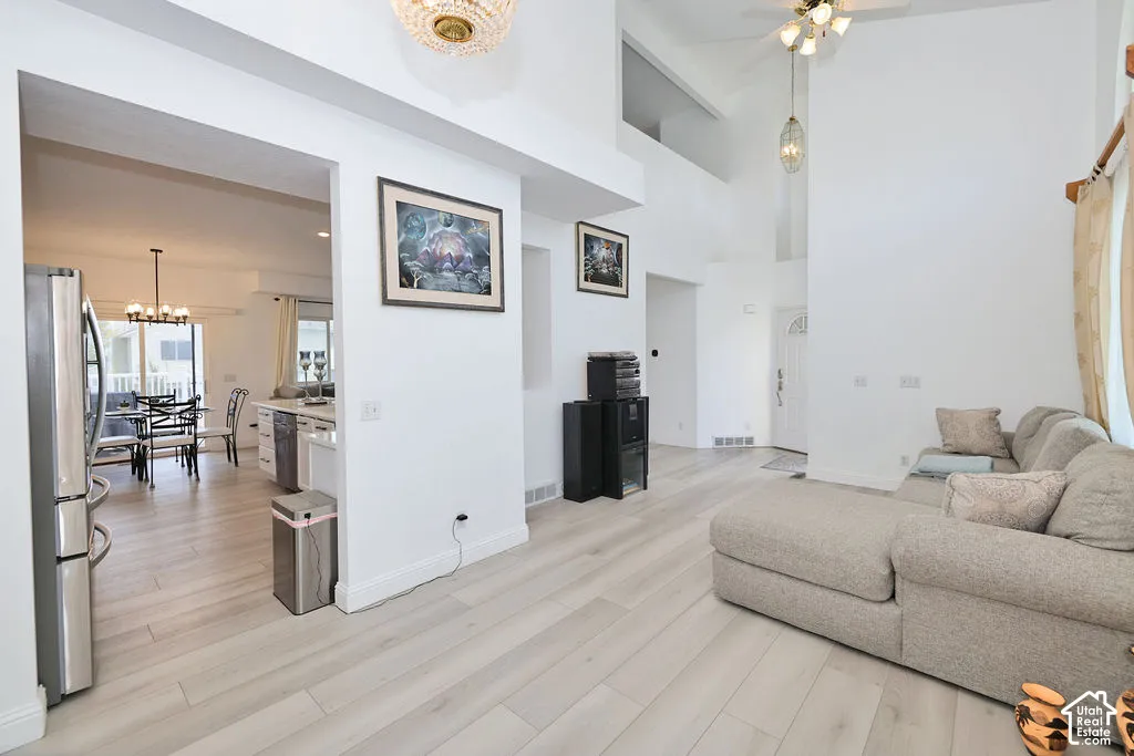 High-ceiling interior space featuring wood-finish flooring, recessed lighting, and decorative crystal-style chandeliers