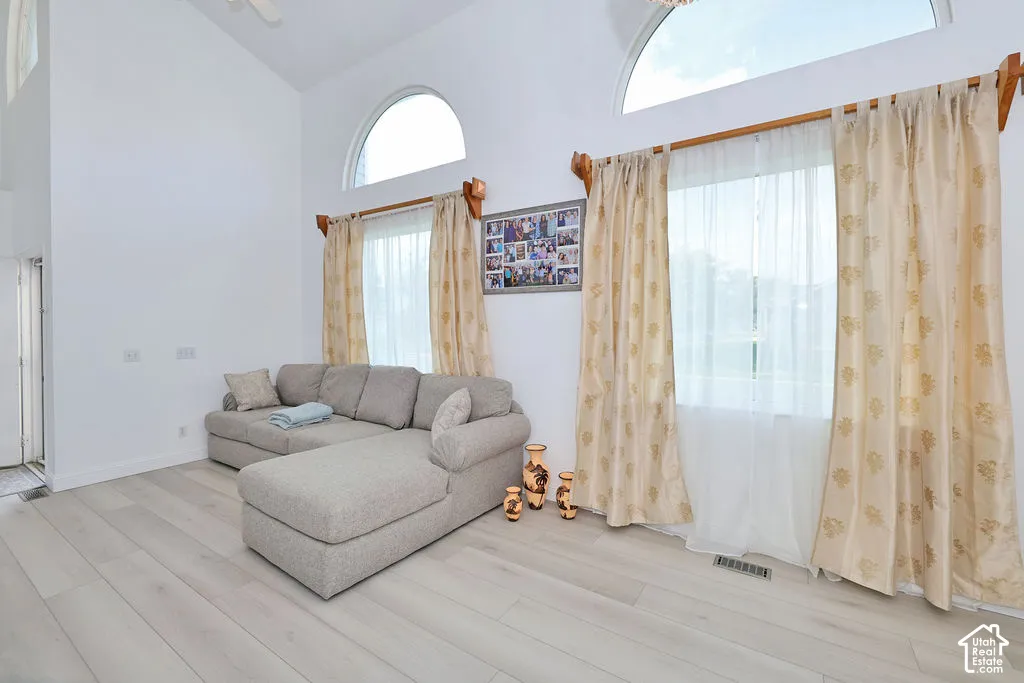 Vaulted ceilings featuring arched windows, light-tone wood-finish flooring, and white wall finishes