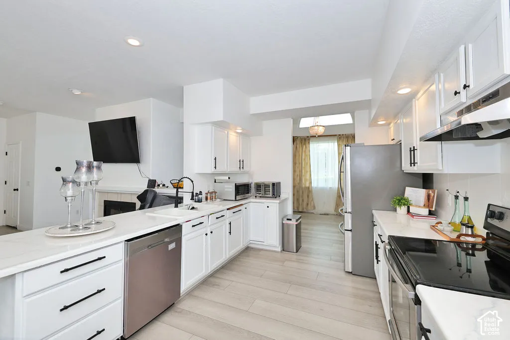 Kitchen featuring white cabinetry with matte black hardware, stone-finish countertops, stainless steel appliances, recessed lighting, and wood-finish flooring