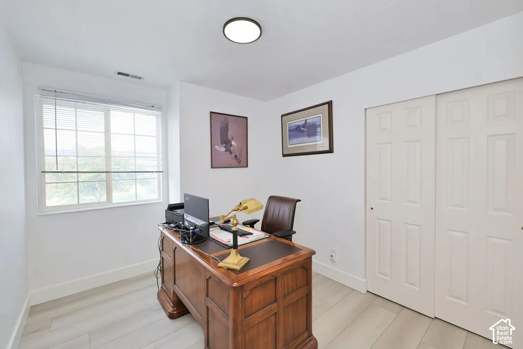 Light-filled room featuring wood-finish flooring, a multi-pane window, flush-mount circular lighting, and a dual-panel sliding closet door