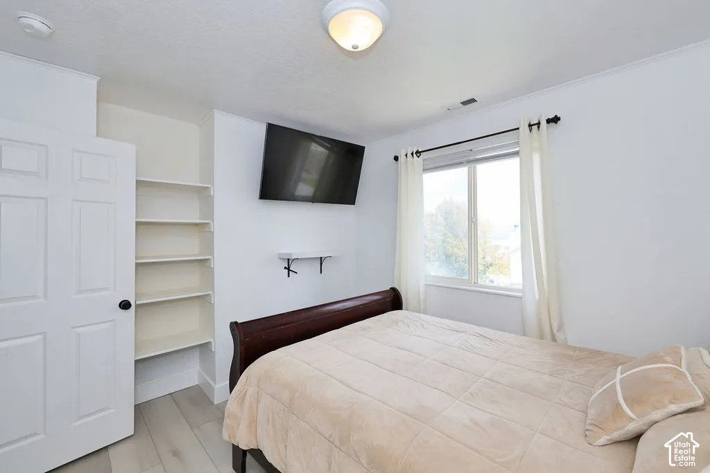 Room featuring wood-finish flooring, built-in shelving, a multi-panel door, and a single-hung window with a rod