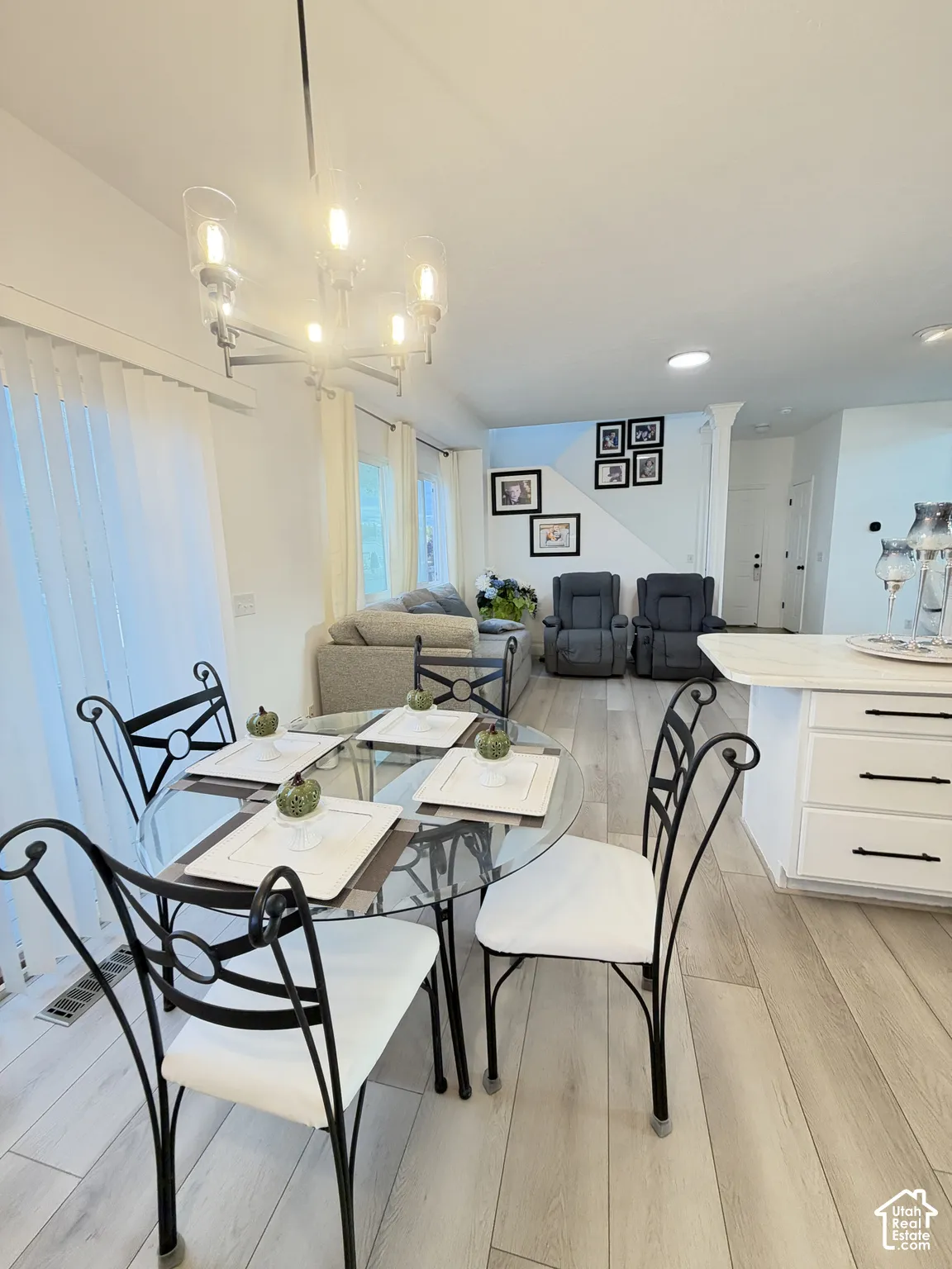 Open-concept space featuring wood-finish flooring, a multi-light metal chandelier, and white cabinetry with dark hardware