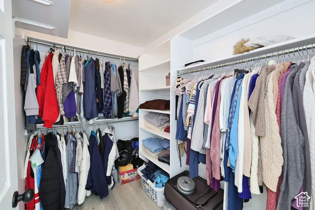 Master Walk-in closet featuring multi-tiered metal hanging rods and white built-in shelving units