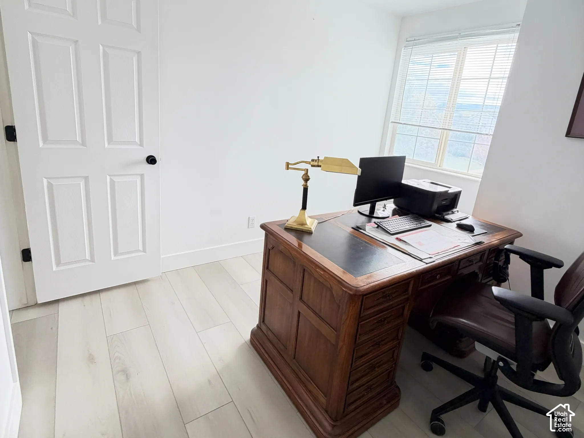 Room featuring wood-finish flooring, a multi-pane window with blinds, and a six-panel door with black hardware