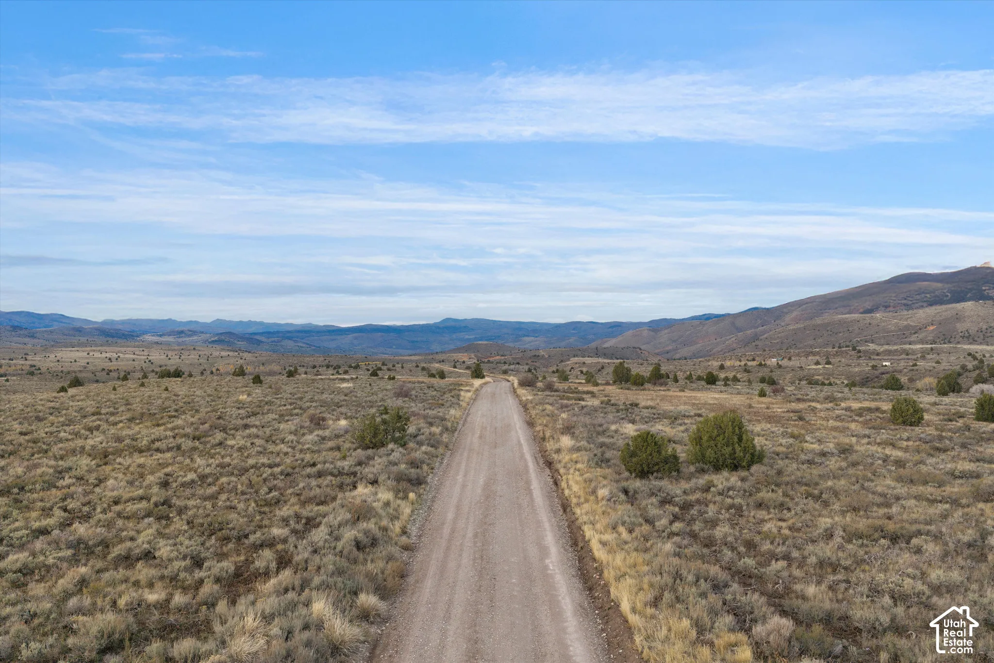 Expansive acreage featuring native shrubbery, terrain topography, and a prominent mountain range backdrop