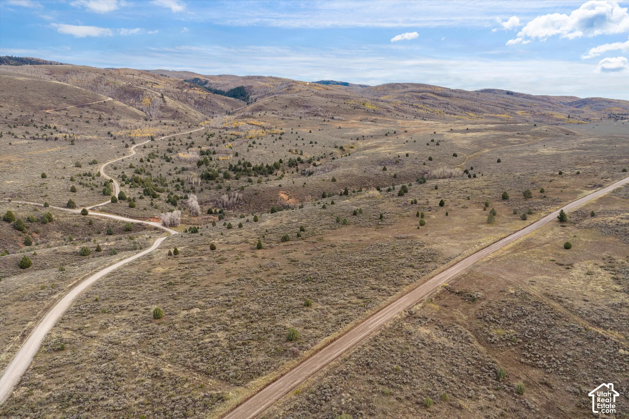 Expansive acreage featuring rugged terrain, native vegetation, rolling hills, and established dirt roadways