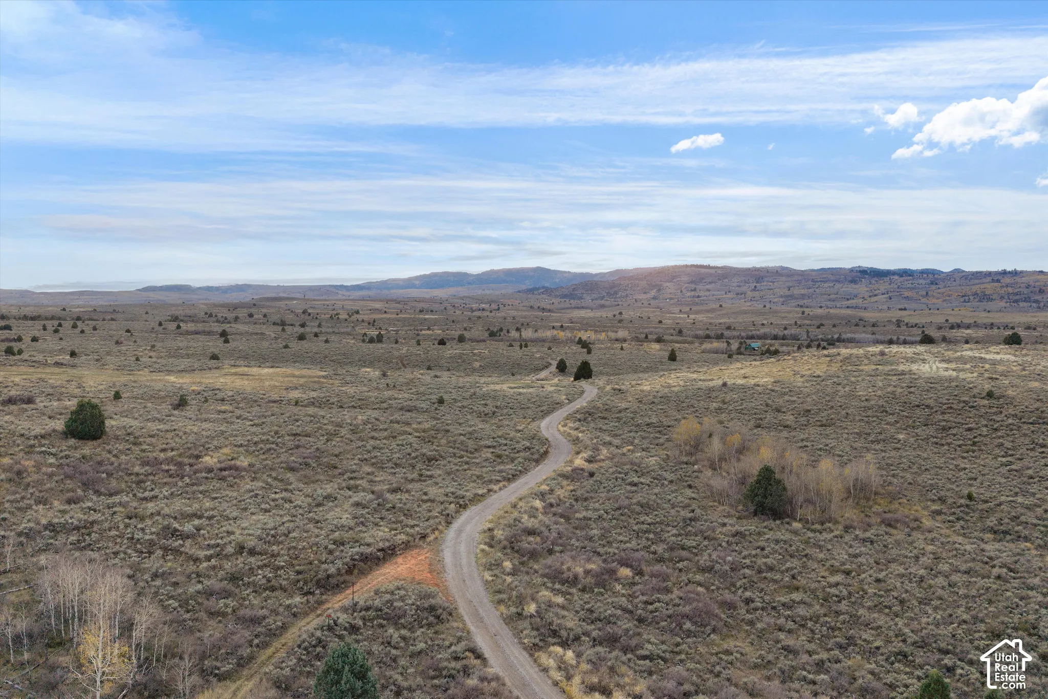 Expansive acreage featuring native high-desert vegetation, a winding gravel access road, and prominent mountain terrain