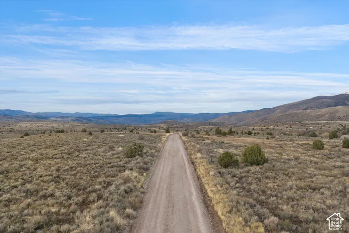 Expansive acreage featuring native shrubbery, terrain topography, and a prominent mountain range backdrop