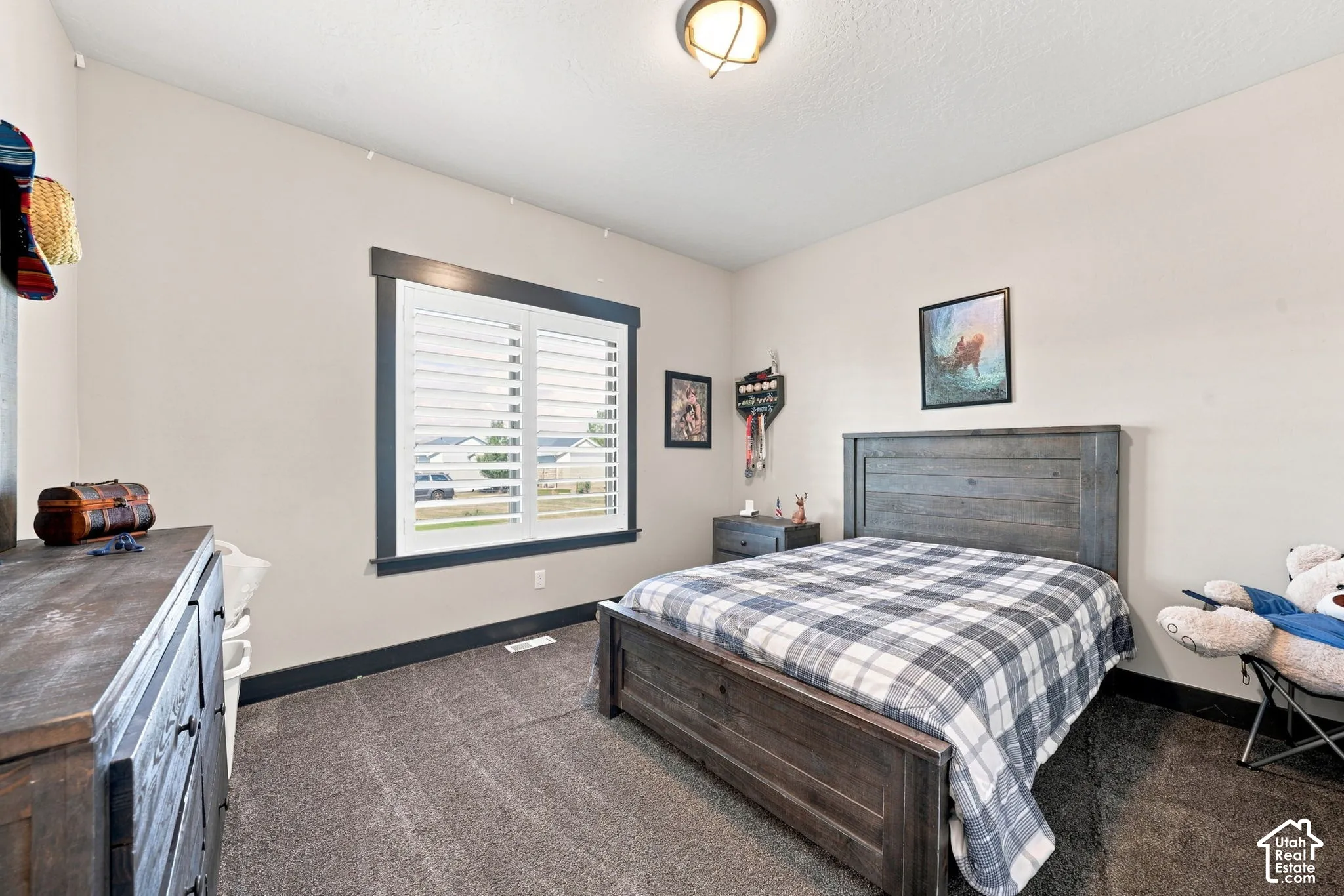 Neutral-toned room featuring high-contrast dark window trim, white plantation-style shutters, ceiling-mounted dome lighting, and wall-to-wall carpeting