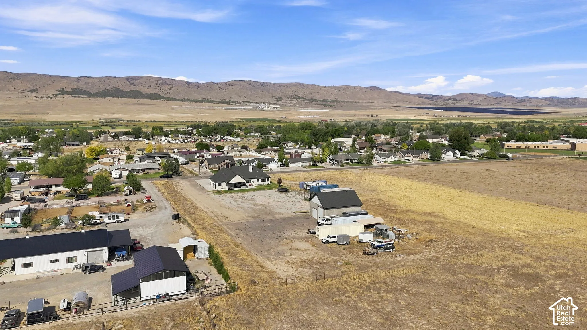 Aerial view featuring expansive acreage, mountain scenery, and multiple detached structures with metal roofing