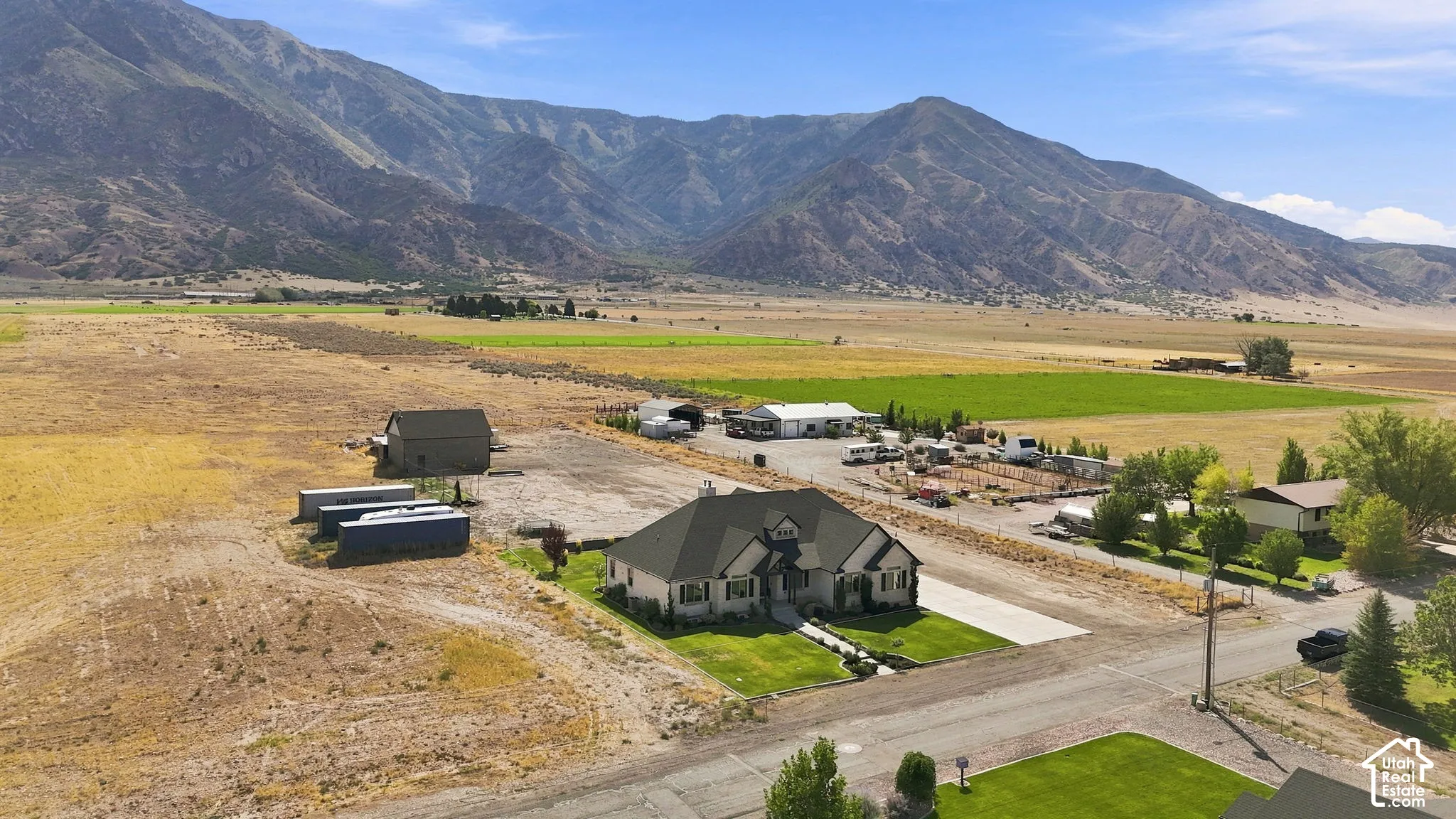 Expansive acreage featuring a multi-structure property, detached storage building, manicured lawn, and mountain backdrop