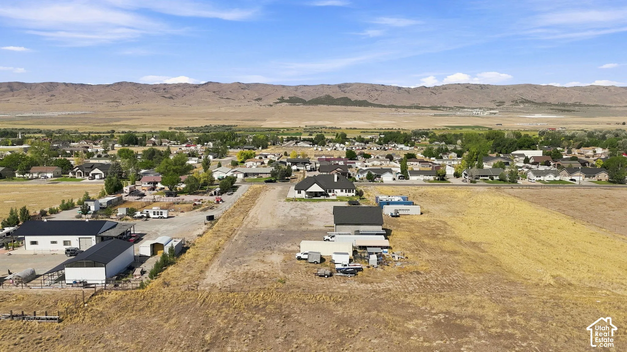 Aerial perspective of expansive acreage featuring multiple detached outbuildings and a backdrop of mountain scenery