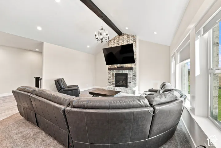 Vaulted ceiling with an exposed wood beam, masonry fireplace with a wood mantel, multi-pane windows, and recessed lighting
