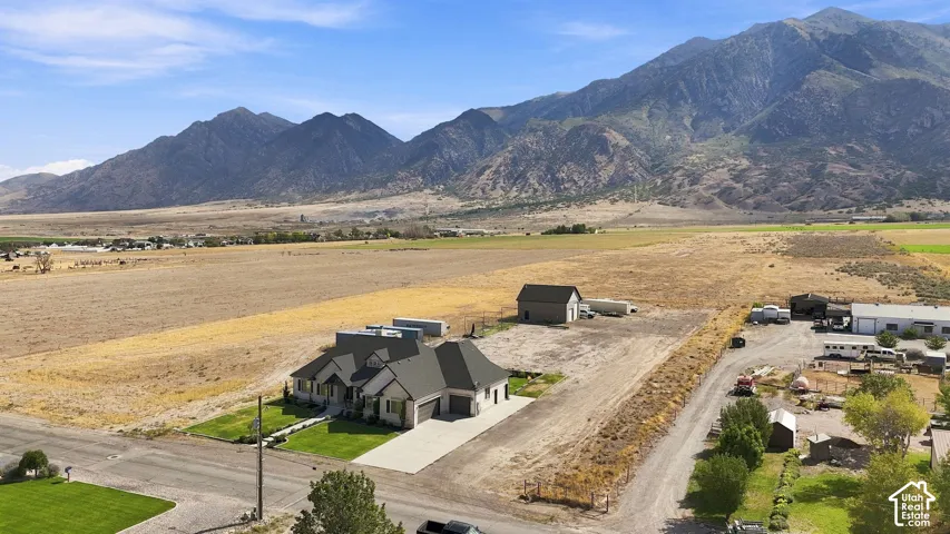 Expansive lot featuring a multi-gabled residence, attached garage, detached outbuilding, and mountain backdrop