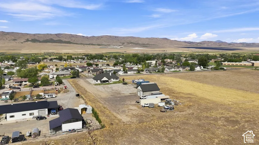 Aerial view featuring expansive acreage, mountain scenery, and multiple detached structures with metal roofing